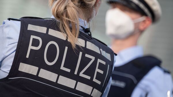 Eine Polizistin und ein Polizist mit FFP2-Maske stehen sich gegenüber., © Marijan Murat/dpa/ZB