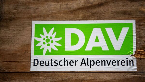 Das Logo des Deutschen Alpenverein (DAV) klebt auf einer Holzbox., © Lino Mirgeler/dpa/Symbolbild