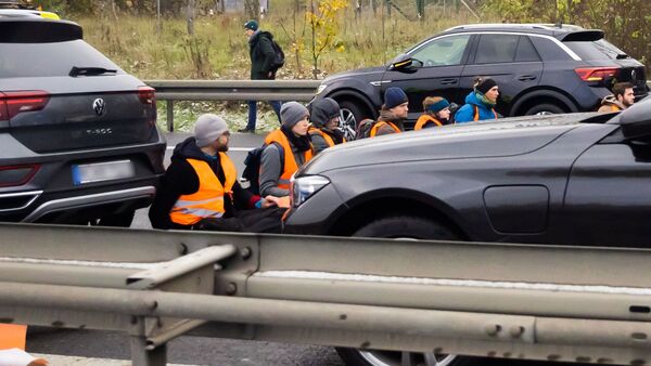 Teilnehmer eines Klimaprotests blockieren auf der A113 kurz vor der Ausfahrt zum Flughafen Berlin Brandenburg (BER)«„Willy Brandt» den Verkehr., © Christoph Soeder/dpa